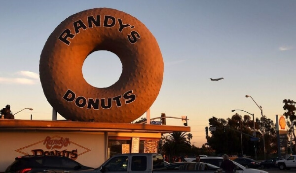 A Randy's donuts outlet shows a large donut sign mounted atop the building