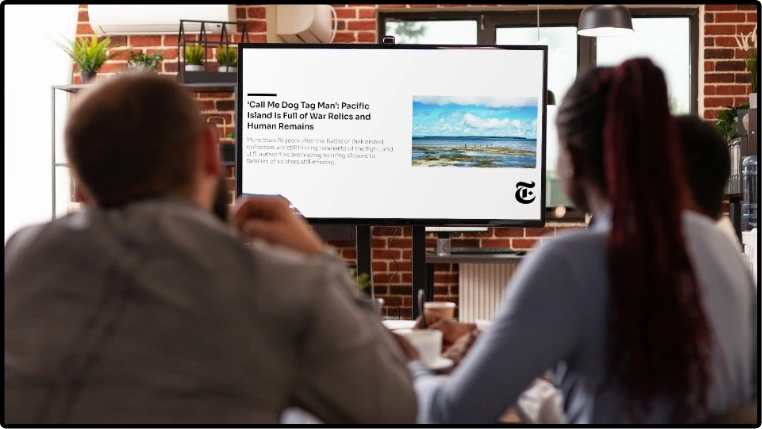 digital signage screen placed at office canteen showing feeds from NYtimes News app with news topic image at right and news text at the left of the screen