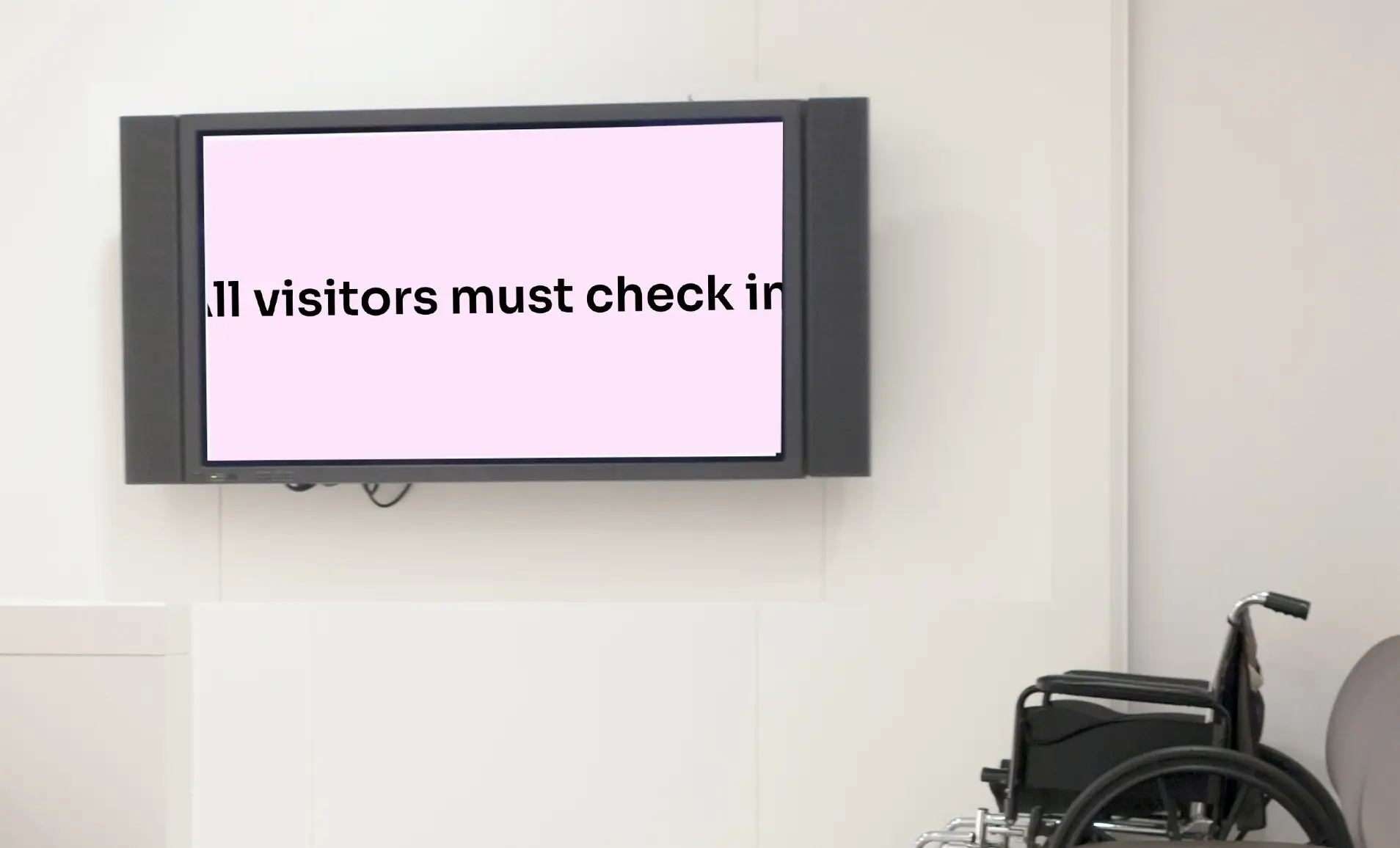 digital signage screen on a hospital lobby dispaying scrolling text about the hospital guidlines.