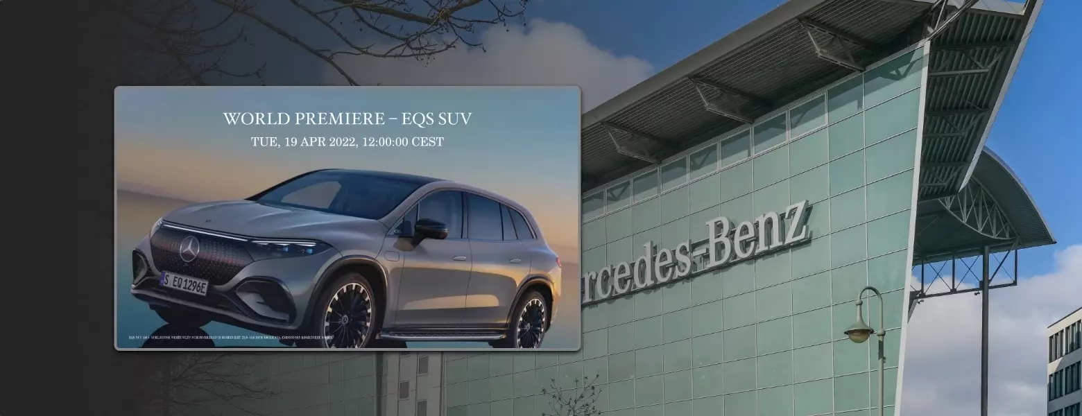 In the foreground of Mercedes-Benz corporate office building, a digital signage display showing the launch of a brand new Mercedes model