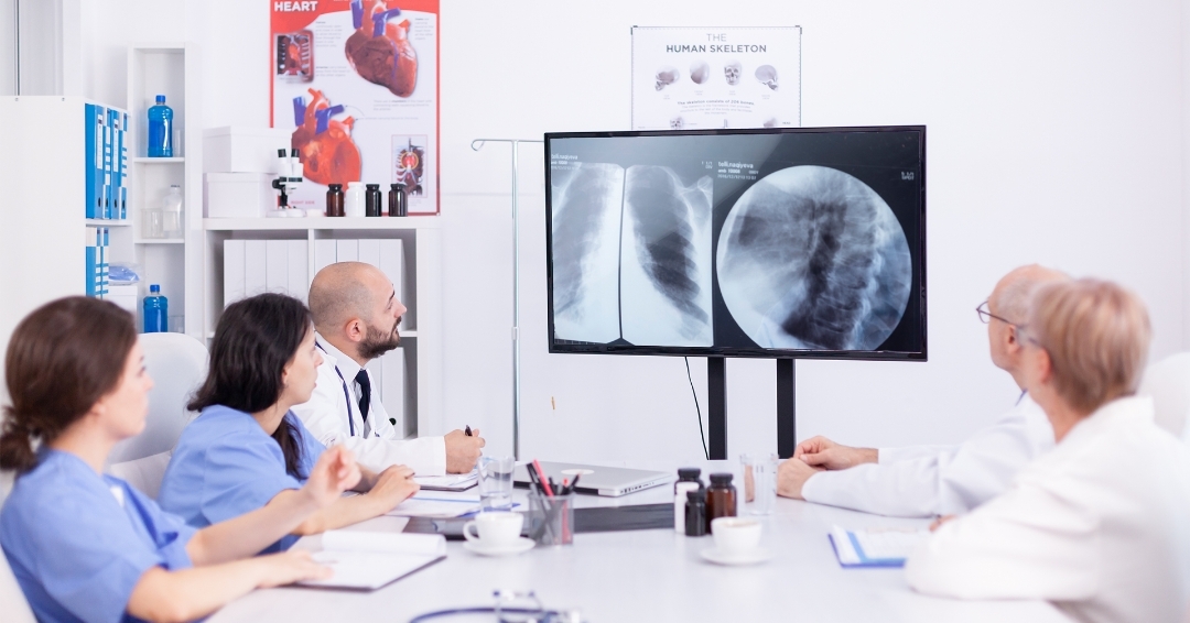 Group of doctors analyzing X-ray that is being displayed on a digital signage screen available in hospital discussion room