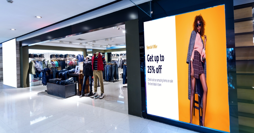 Digital Signage at the entrance of a retail clothing store displaying content about ongoing promotions 