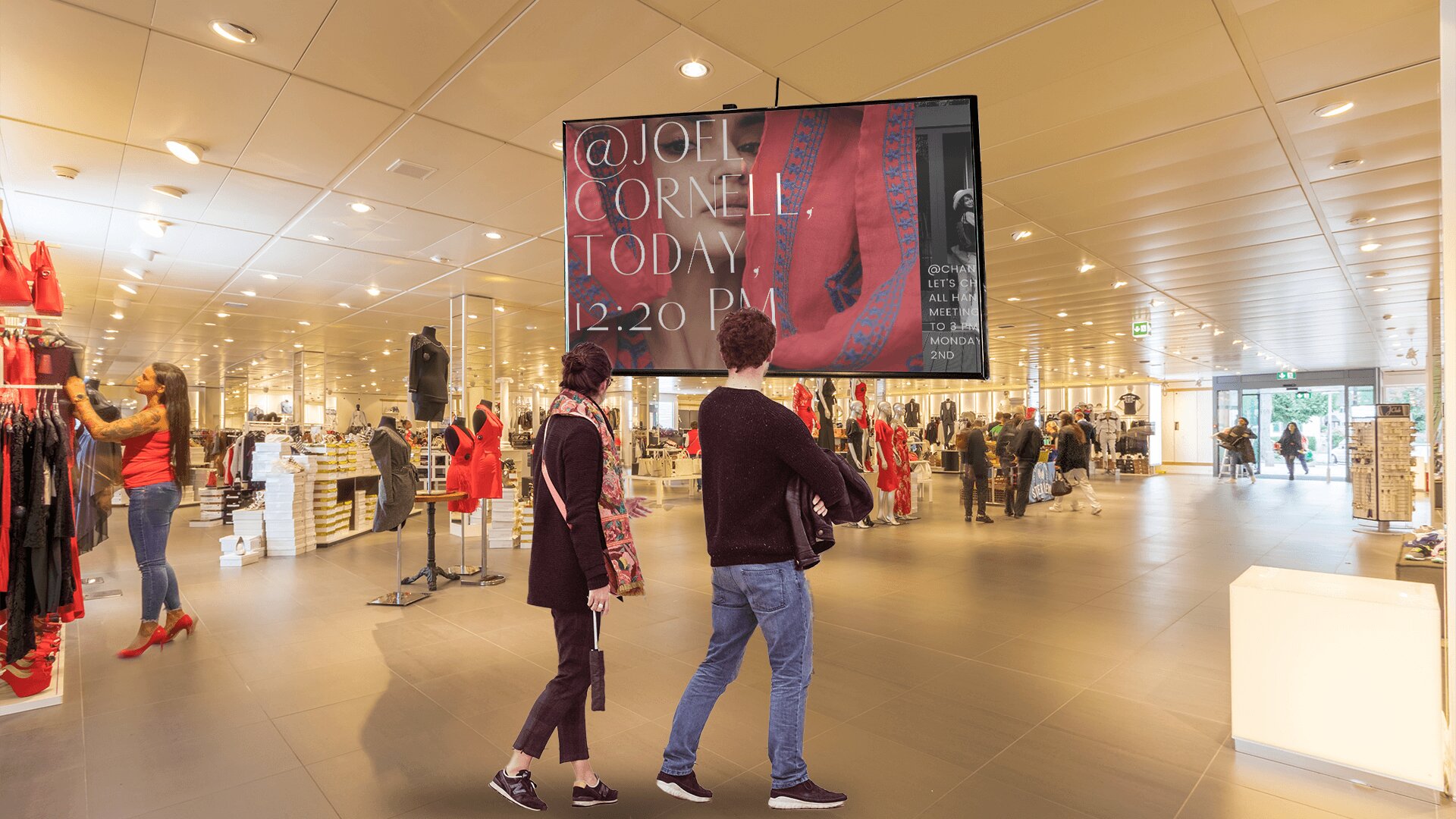 Two shoppers gaze at a video ad playing on the digital signage display installed inside a retail clothing store.