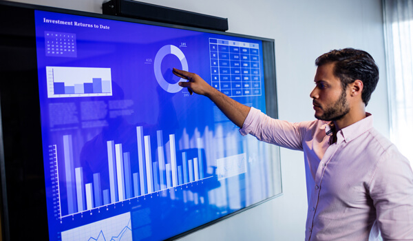 sales head analysing the sales and marketing dashboard displayed on the digital signage tv screen in a meeting room