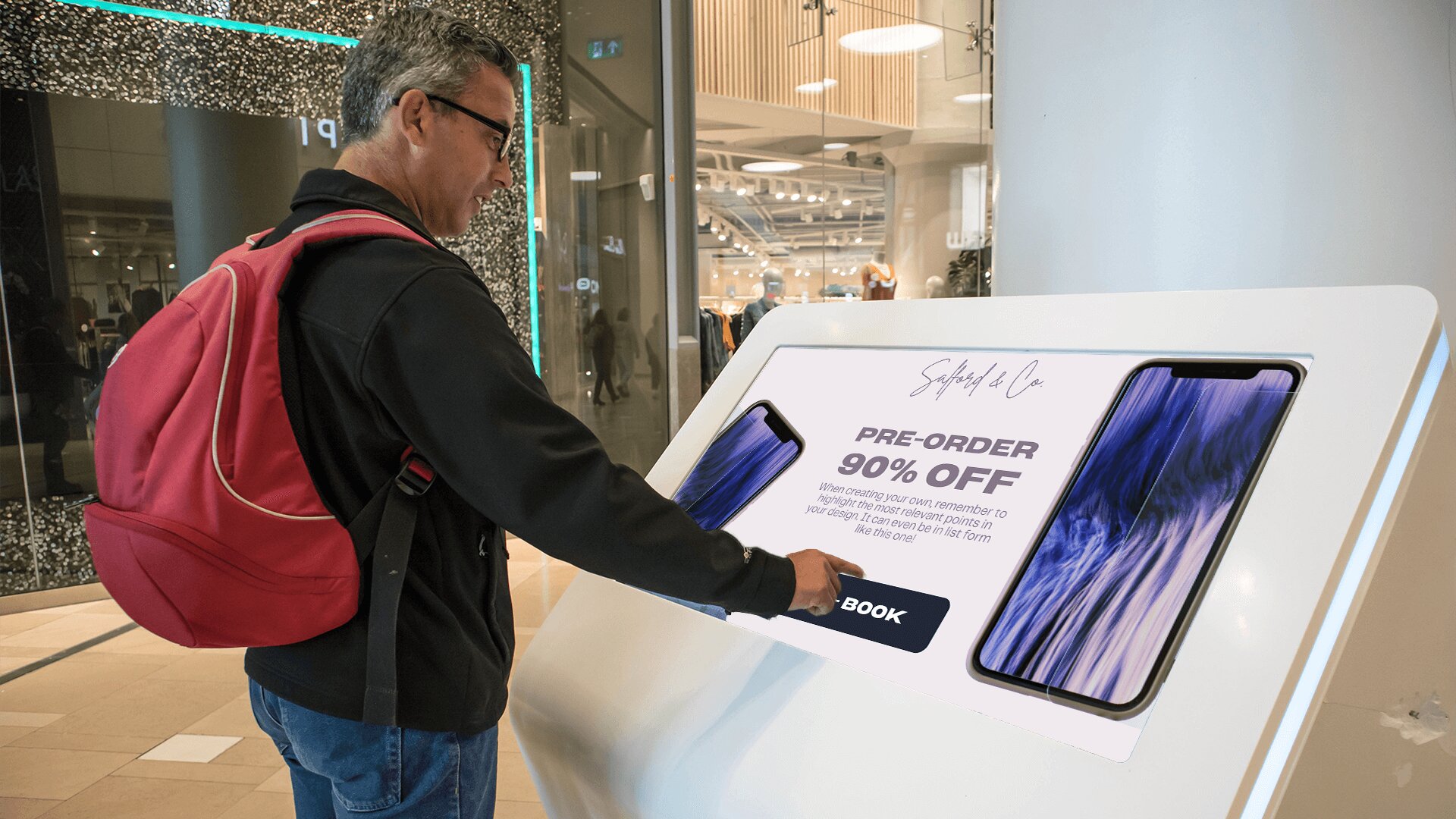 A man in a black sweatshirt interacts with a kiosk showing the digital product catalogue of newly-launched smartphones.