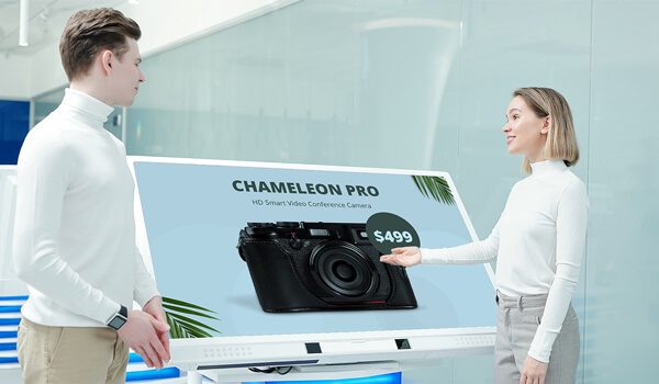 Large digital standee shows the HD image of a Chameleon Pro camera model with its price. A sales lady shows this digital product catalog to a customer