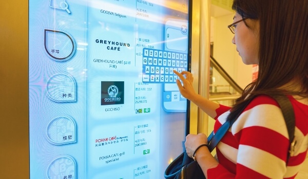 A woman typing on the virtual keyboard of a touchscreen digital reader board to find out necessary information