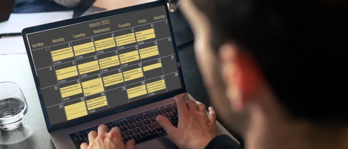 A man works on a digital signage calendar on his laptop screen