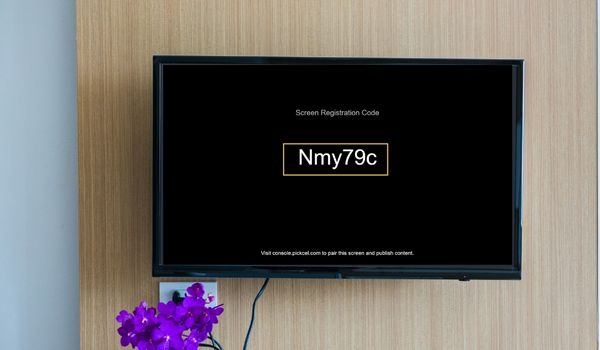 A digital signage display shows Pickcel's 6-digit screen registration code for device pairing