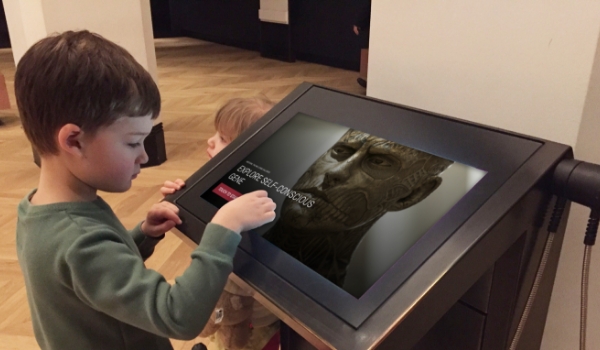a boy using touchscreen information kiosk in museum get information about the art.
