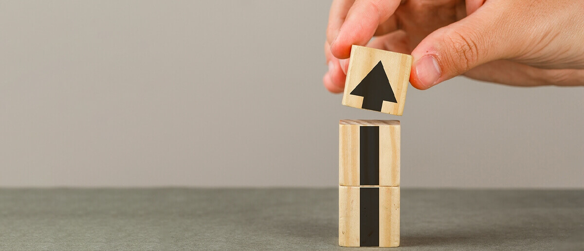 person stacking blocks with an arrow upward representing building a digital signage strategy