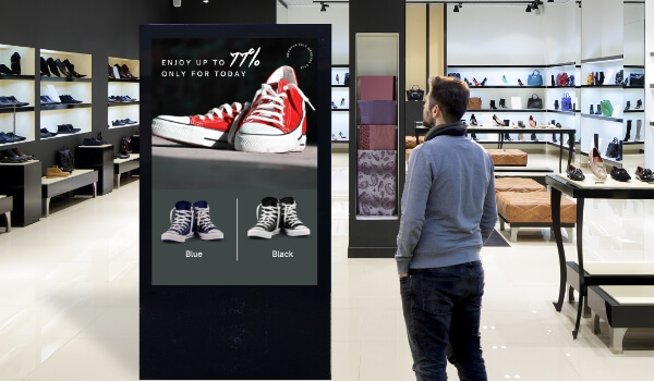 customer looking at a digital product catalog for shoes on a digital signage with the help of pickcel software