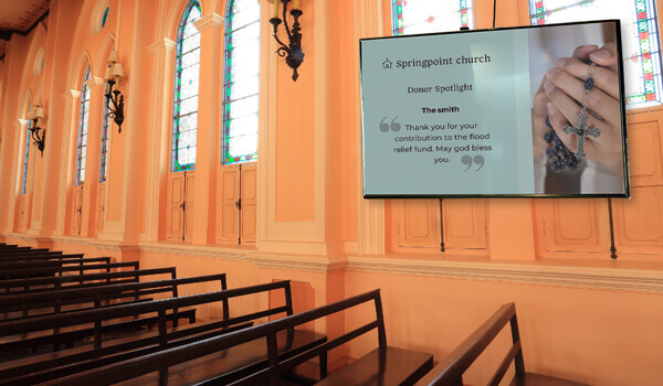 An HD church digital display broadcasts a thank you message to a donor. The message is decorated with the image of a hand folded into prayer