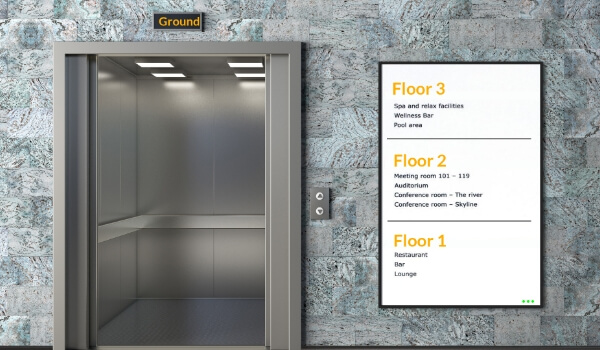 A digital signage display outside an elevator showing what each floor of the building offers