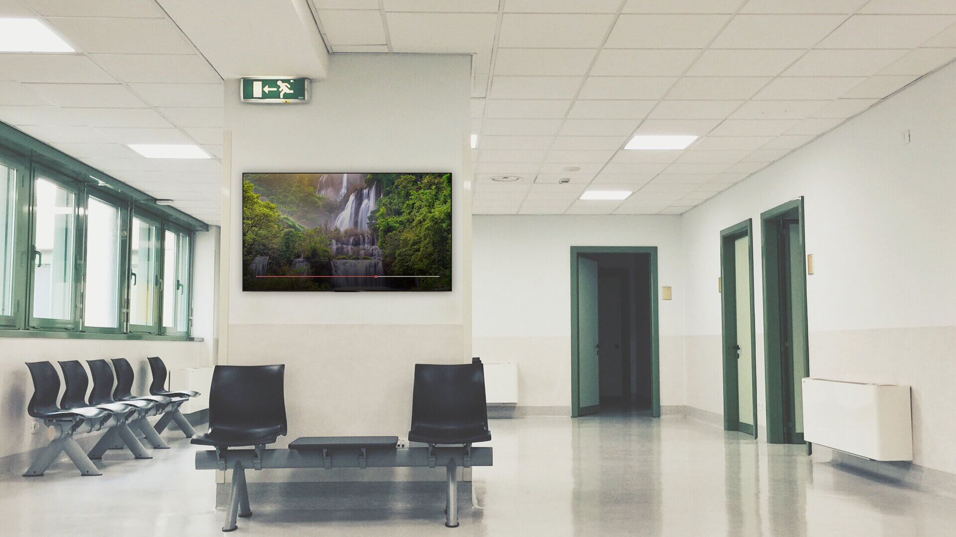 A digital screen installed in an empty hospital waiting room shows soothing visuals to enhance the patient experience.