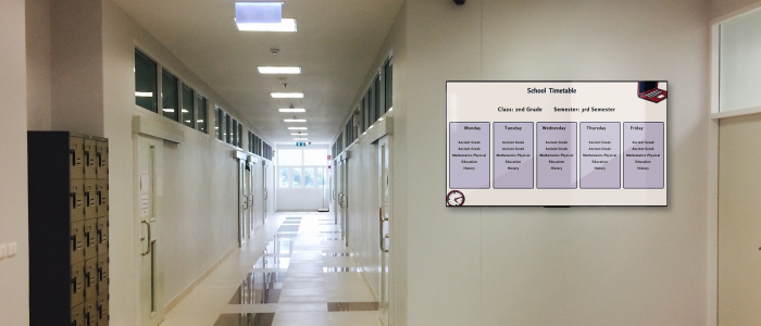 A wall-mounted digital screen in a school corridor shows weekly class schedules of the second-grade