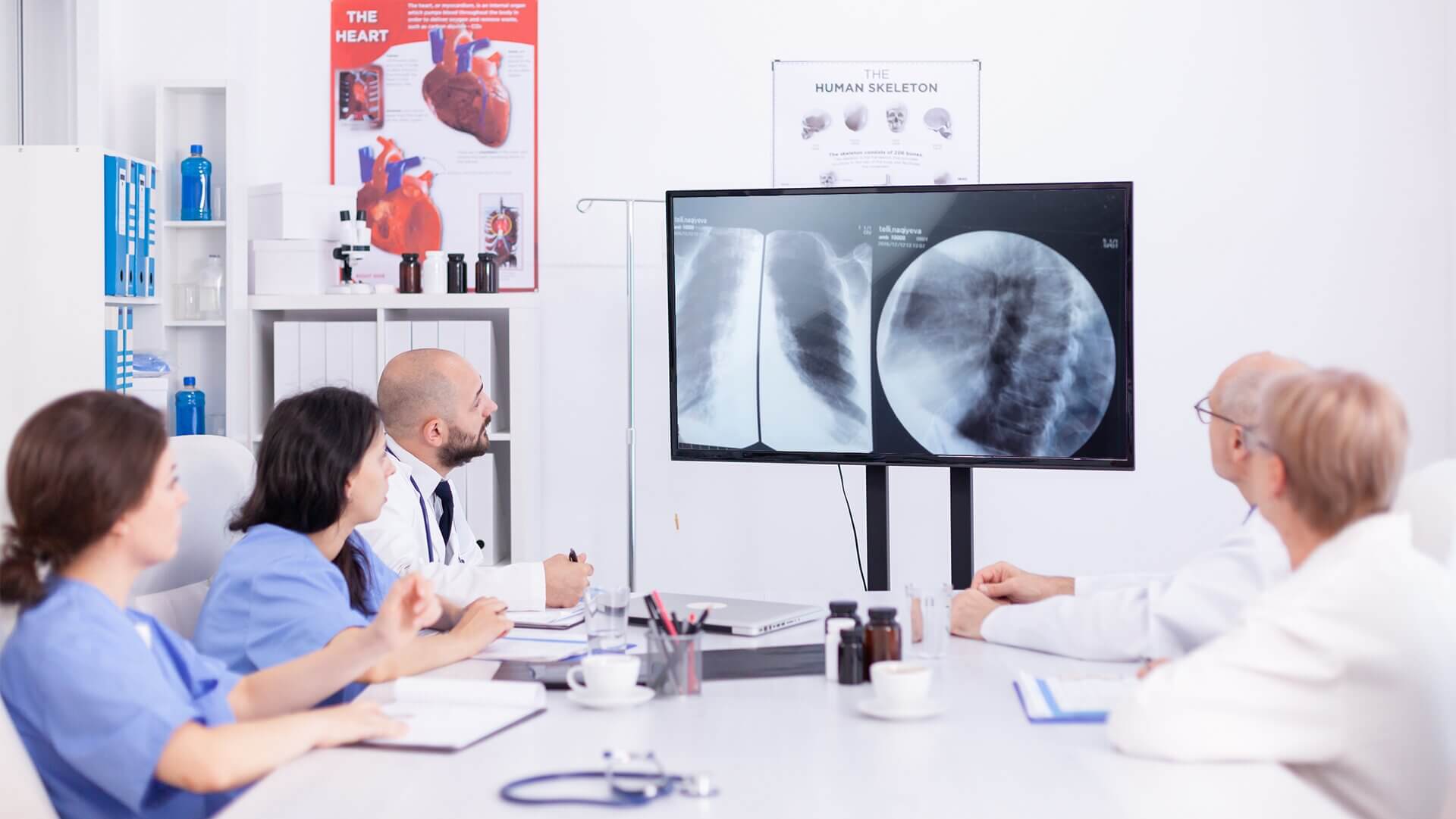 A group of doctors and nurses discussing a patient&rsquo;s chest X-Ray with digital signage screen.