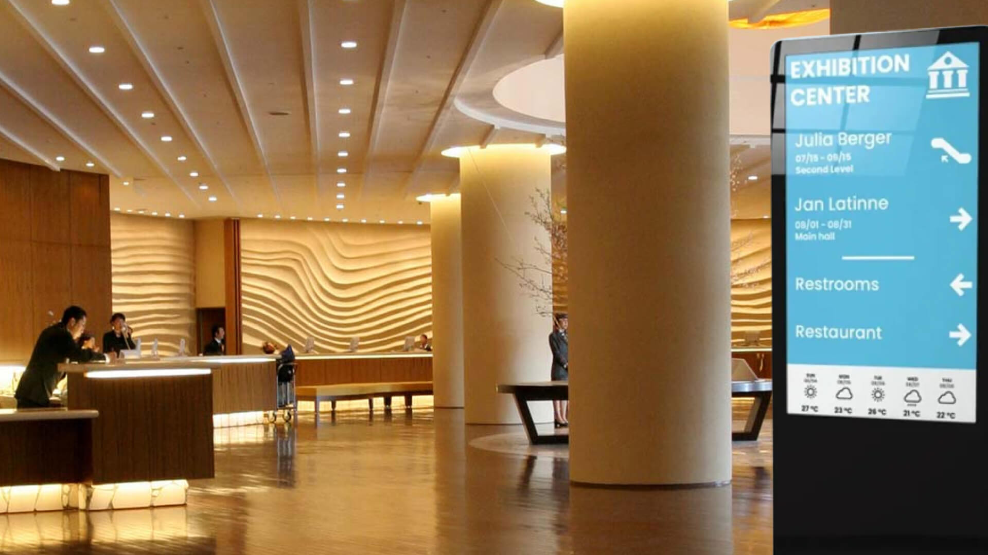 A hotel reception with digital signage kiosk showing event schedules.