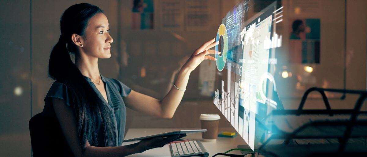 A woman interacts with a futuristic software on a PC monitor