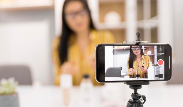 an influencer recording a video on mobile phone about make up and fashion products