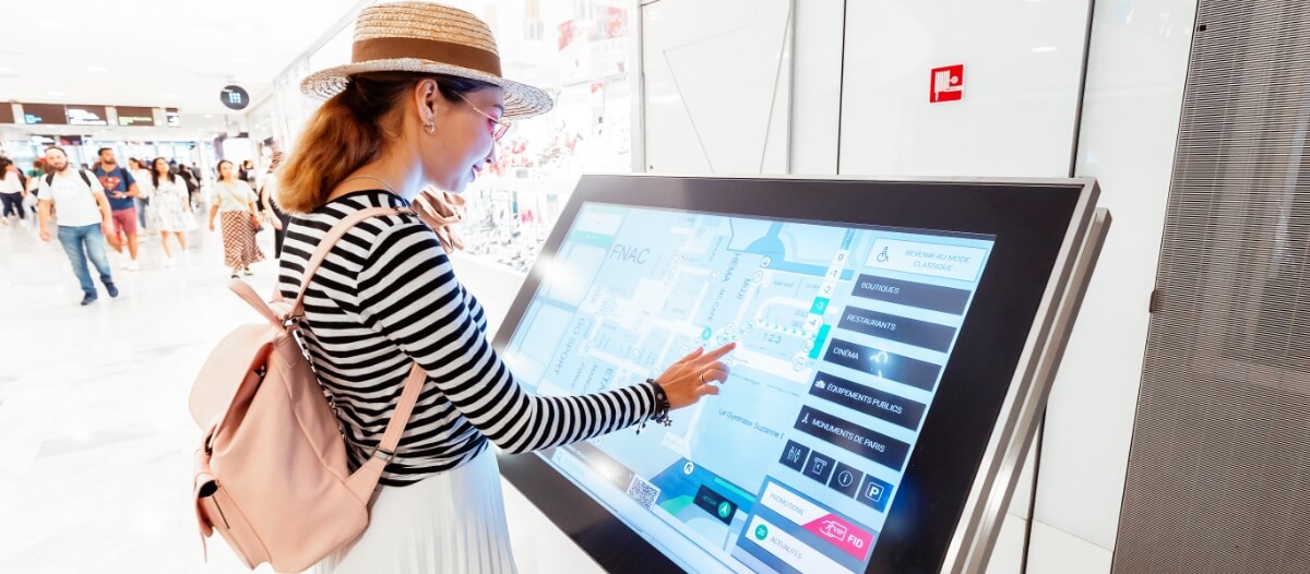  A woman interacting with a touchscreen wayfinding digital signage by touching the relevant icons and tabs