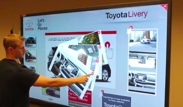 A man discovering features and specifications of a Toyota car by interacting to a touchscreen digital signage