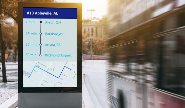 A curbside Passenger Information Display System (PIDS) shows the route of a bus