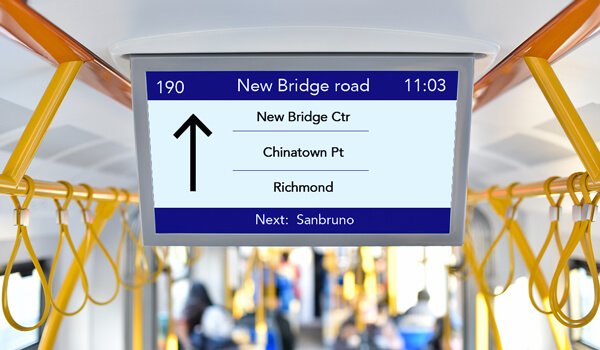 An on-board display inside a public bus shows the live vehicle route, upcoming bus station with ETA
