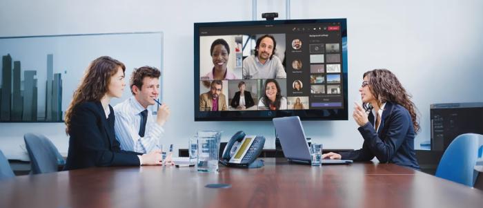 Employee in an office corridor reading a Teams announcement displayed on a Pickcel digital signage screen