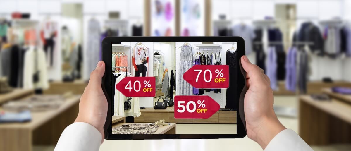 A person holds a digital tablet inside a clothing store representing phygital retail