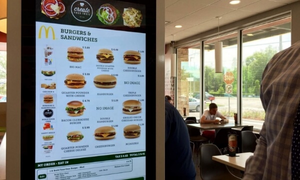 A McDonald's interactive digital menu board displays varieties of burgers with tempting images