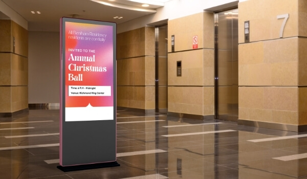 A bright colorful digital poster at a building entrance invites the residents to an Annual Christmas Ball