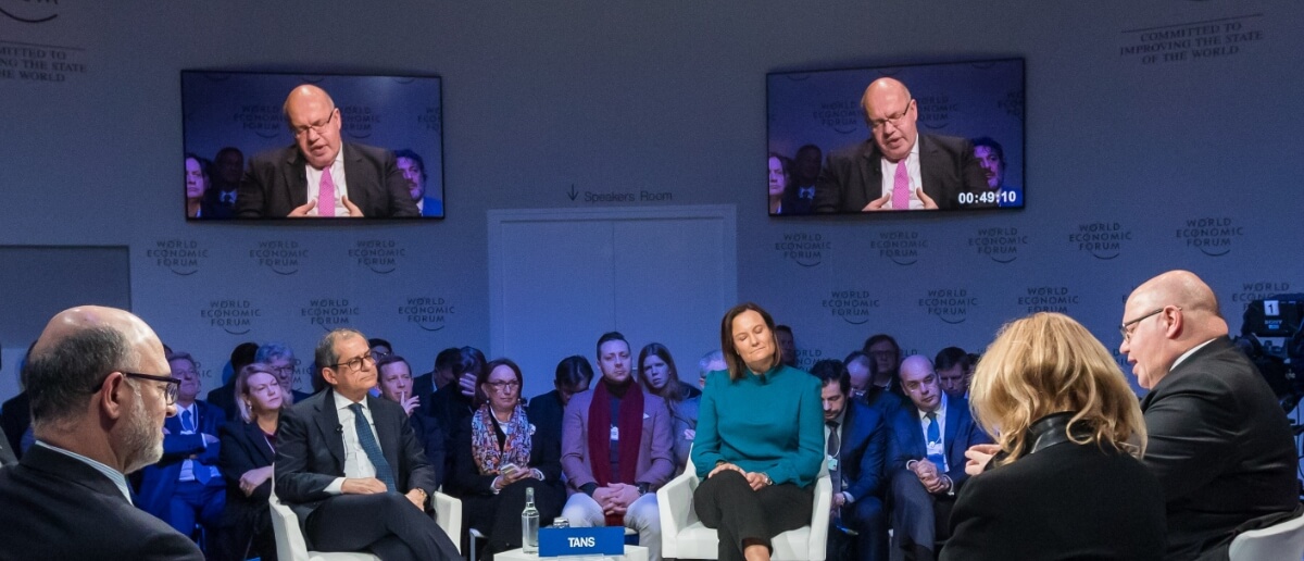 A panel discussion being live-streamed on a digital signage screen