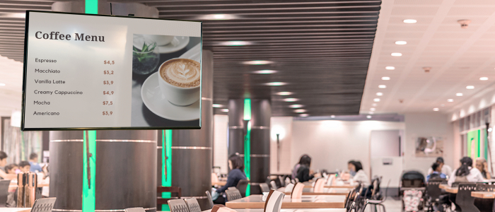 A school cafeteria shows a digital menu with a bright image on a large signage display