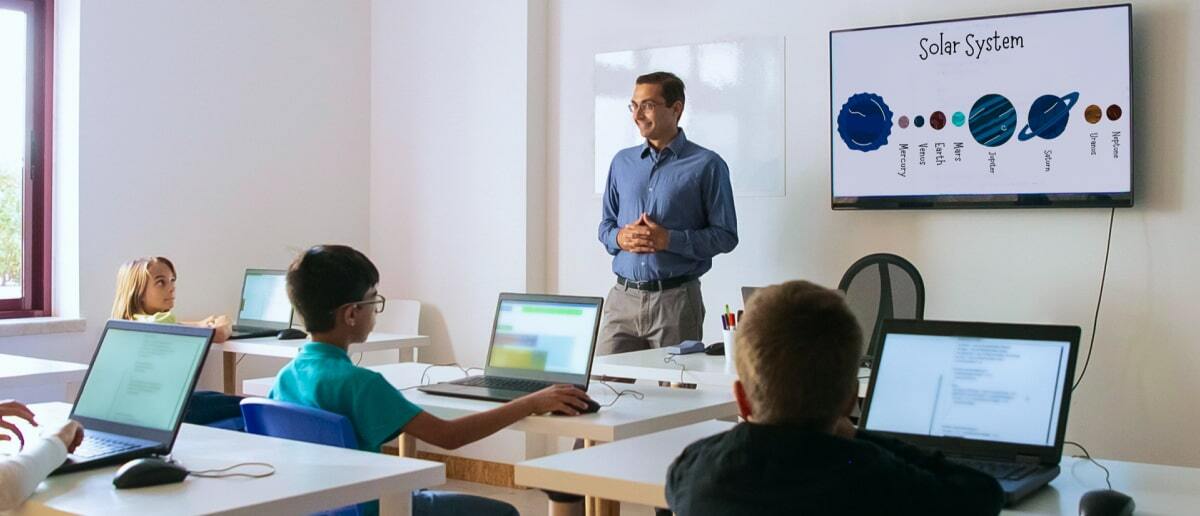 teacher explaining solar sytem to students using digital signage in school classroom