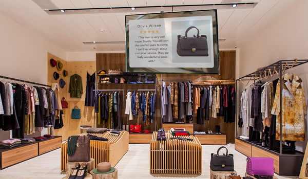 A retail store shows 5-star testimonial for a leather bag on their digital signage display.