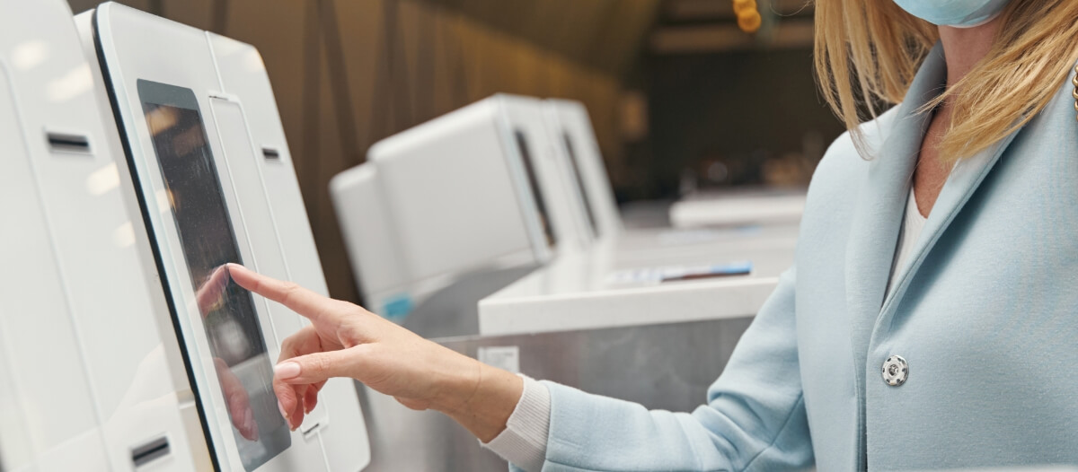 A woman in a blue coat interacts with a smart touch screen digital signage kiosk