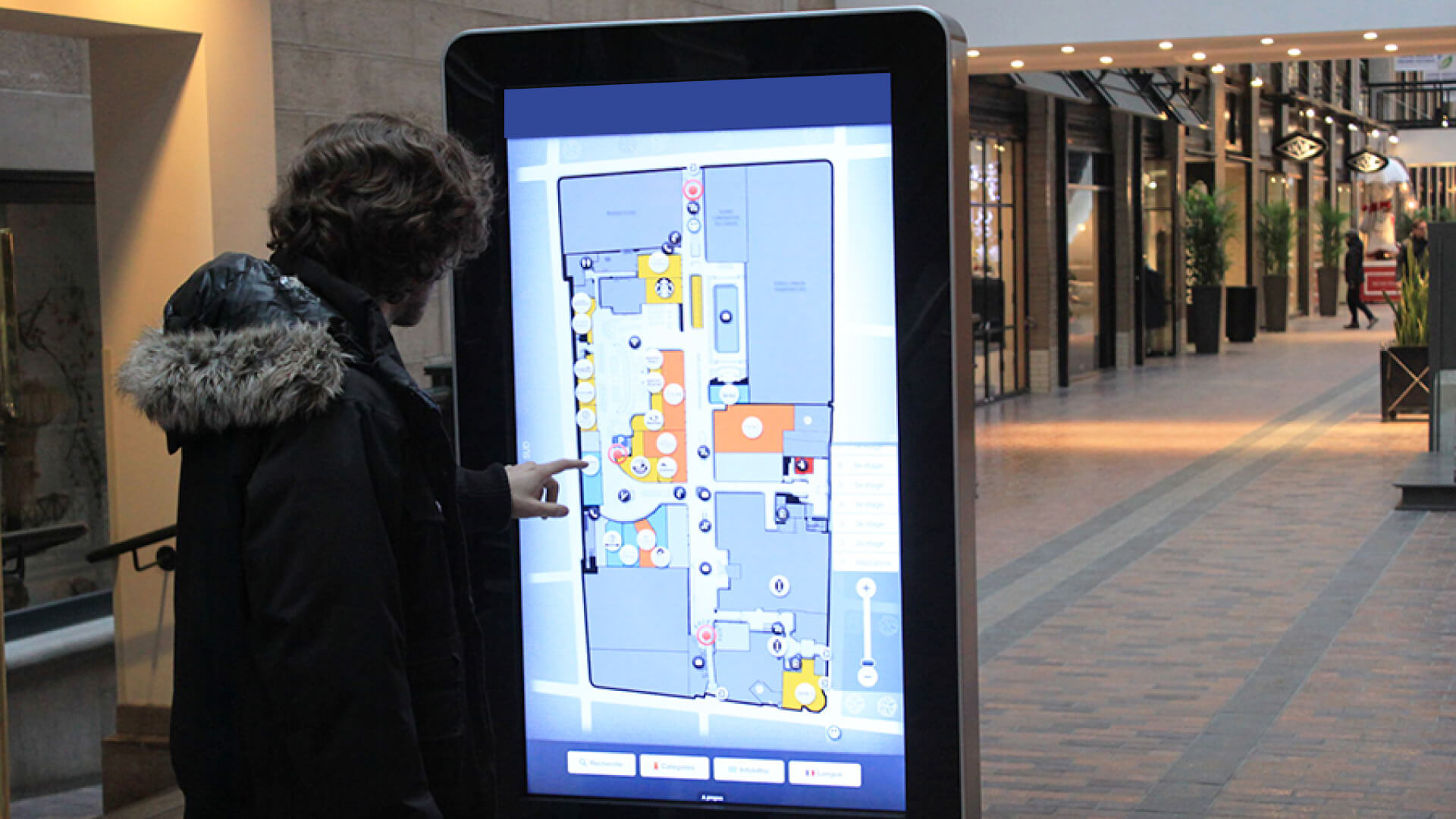 A man near a stadium interacts with a digital wayfinding map