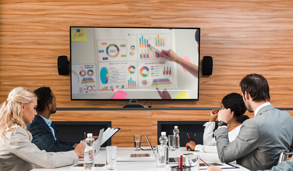 marketing team inside a meeting room watching a training video playing on digital signage TV screen