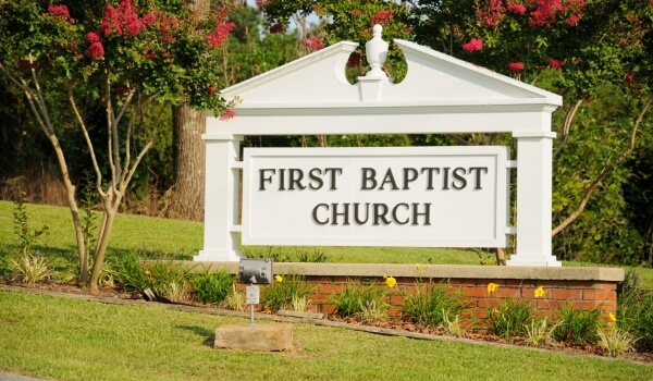 A white monument sign outside a church shows the name of the church