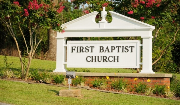 A white monument sign outside a church shows the name of the church