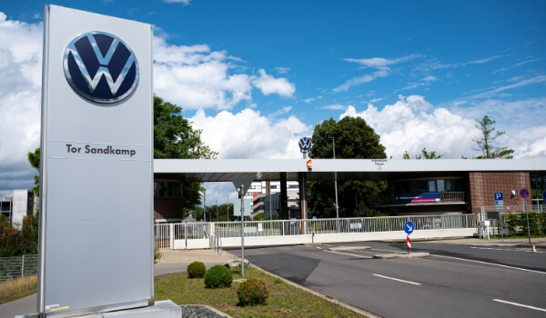 A white pylon sign near a highway toll plaza shows the stylish BMW logo