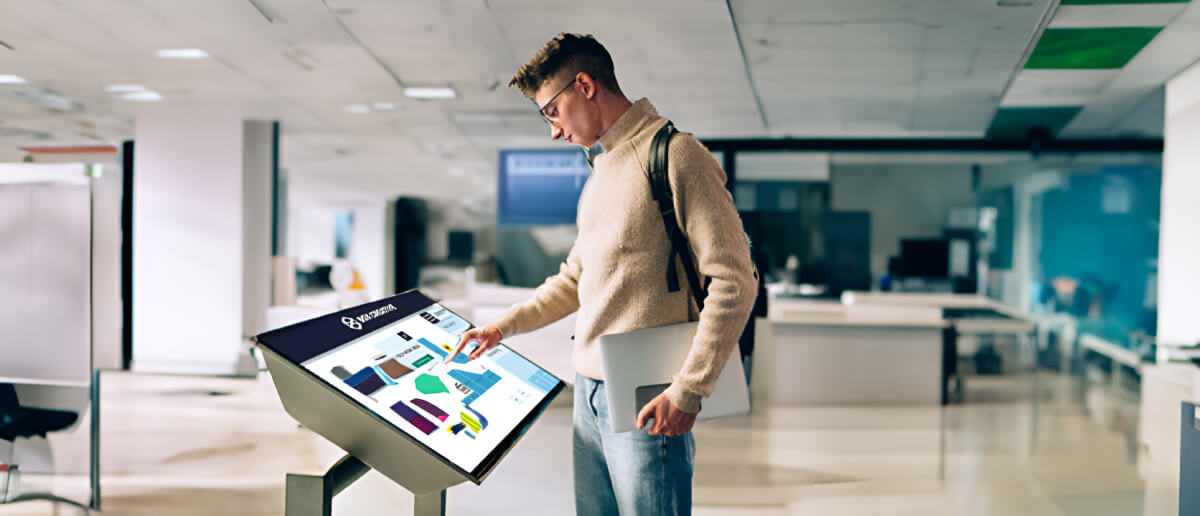An employee using digital wayfinding kiosk in office.