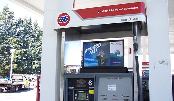 A gas station digital signage shows an advertisement on the pump top